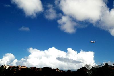 Low angle view of airplane flying against cloudy sky