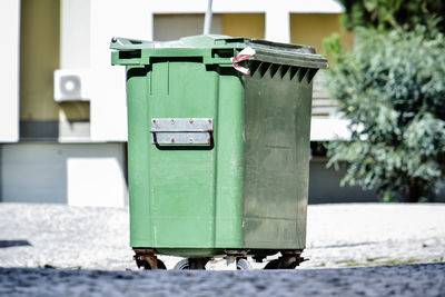 Close-up of garbage can against white wall in city