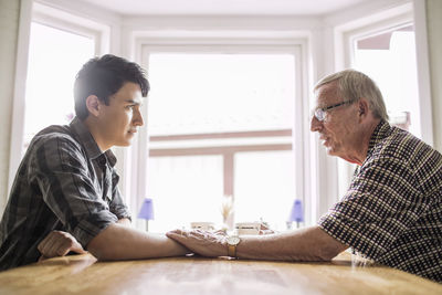 Side view of grandfather consoling grandson at table