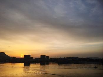 Silhouette city buildings against sky at sunset