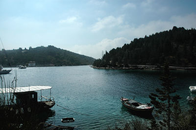 Boats moored at harbor by sea against sky