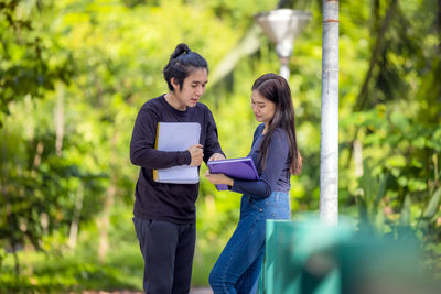 Young woman standing against plants