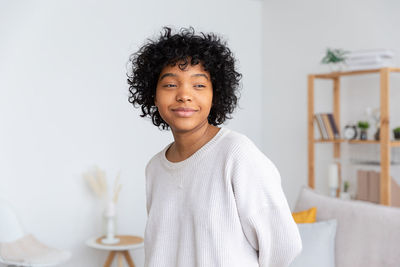 Portrait of young woman standing against wall