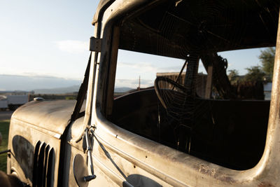 Close-up of abandoned car against sky