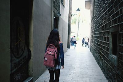 Rear view of woman walking on footpath in city