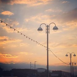 Low angle view of silhouette street light against dramatic sky during sunset