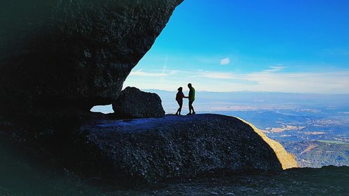 People standing on rock by sea against sky