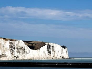 Built structure by sea against blue sky