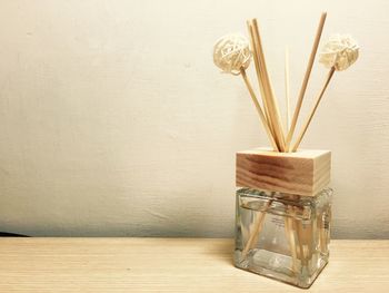 Wooden sticks in container on table against wall