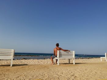 Rear view of shirtless man looking at beach