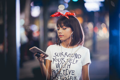 Close-up of young woman using mobile phone at night