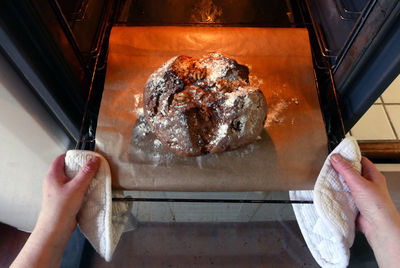 Cropped hands of woman baking bread in microwave at home