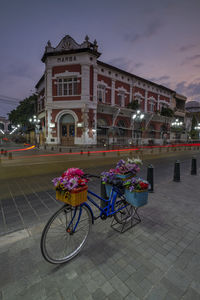 Bicycle parked on footpath by building against sky