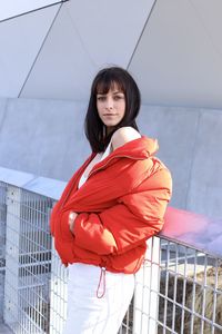 Portrait of woman standing against red wall