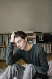 Upset young man with head in hand sitting at home