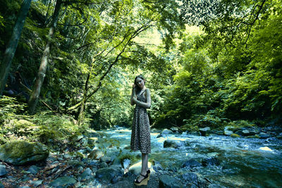 Woman standing by tree in forest