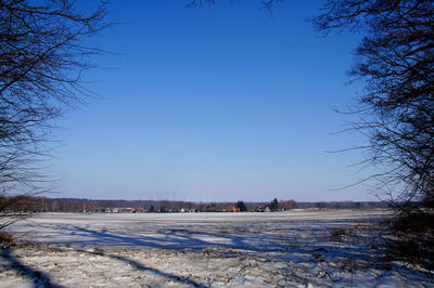 Scenic view of frozen landscape against clear blue sky