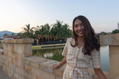 Portrait of smiling young woman standing against sky