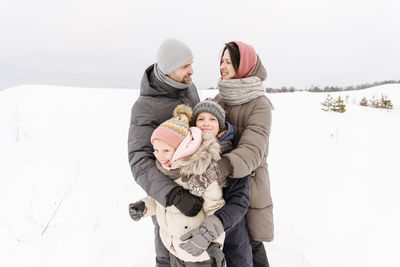 Family enjoying vacation on snow covered landscape against sky