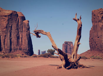 Driftwood on rock formations in desert against sky