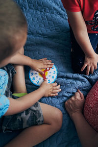 High angle view of people sitting by toy clock on bed