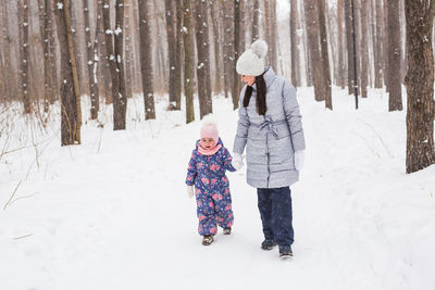 Rear view of people on snow covered trees during winter