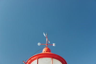 Low angle view of weather vane against blue sky