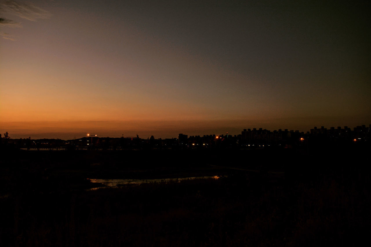 ILLUMINATED CITY AGAINST SKY AT SUNSET