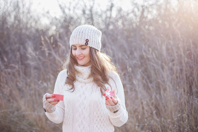 Portrait of smiling young woman standing on smart phone