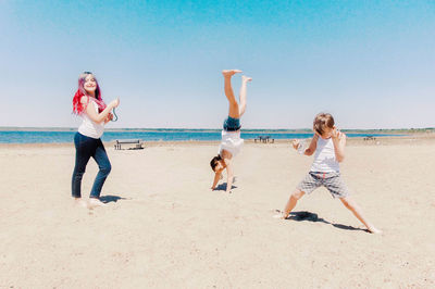 Siblings with mother playing at beach against sky