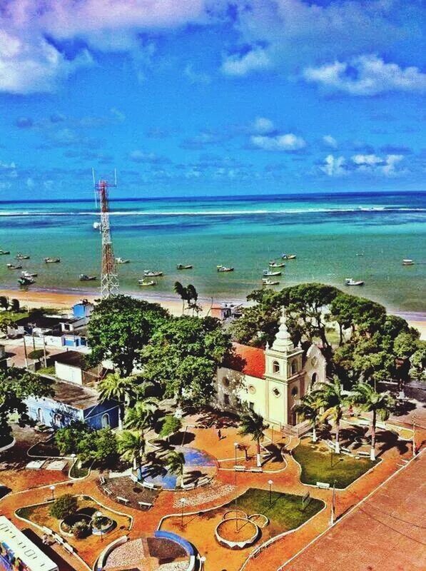 sea, building exterior, architecture, built structure, sky, horizon over water, water, cloud - sky, high angle view, beach, house, town, tree, cloud, blue, residential structure, city, incidental people, shore, residential building