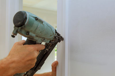 Close-up of cropped hand using nail gun on wood