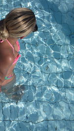 High angle view of young woman wearing bikini while standing in swimming pool