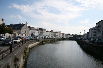 River amidst buildings in city against sky