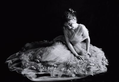 High angle view of girl sitting in wedding dress over white background