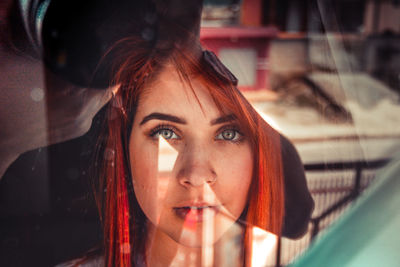 Close-up portrait of young woman reflecting on window