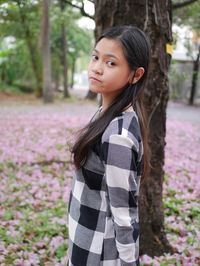 Portrait of young woman standing against trees