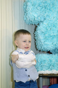 Portrait of happy boy standing against wall