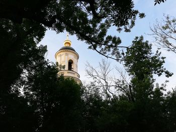 Low angle view of trees and building against sky