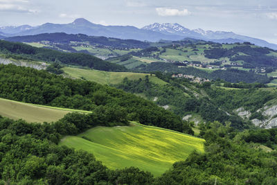 High angle view of green landscape and mountains against sky