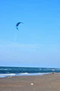 Man flying over beach against sky