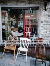 Empty chairs and tables at sidewalk cafe against building