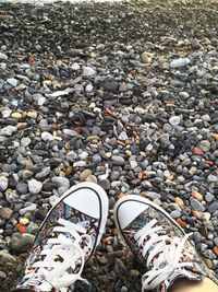 Close-up of cropped shoes on pebbles