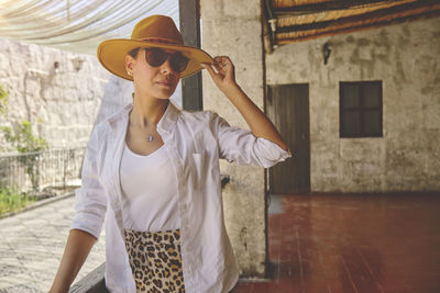 Woman wearing cowboy hat sitting on porch, jalisco mexico, portrait of happy woman using hat. 