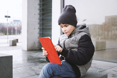 Close-up of boy using digital tablet while sitting outdoors