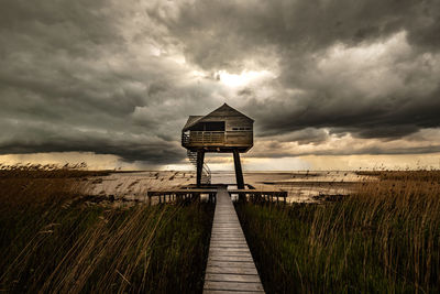 Boardwalk on field against sky