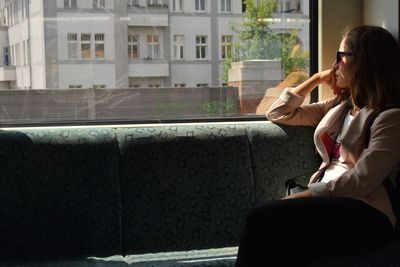 Thoughtful woman wearing sunglasses looking through window at home