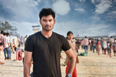 Portrait of young man standing on land against sky