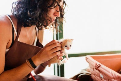 Midsection of woman holding kitten in workshop