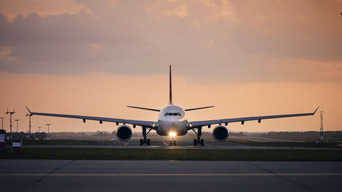 Wide-body airplane taxiing for take off. front view of plane against airport at sunset.